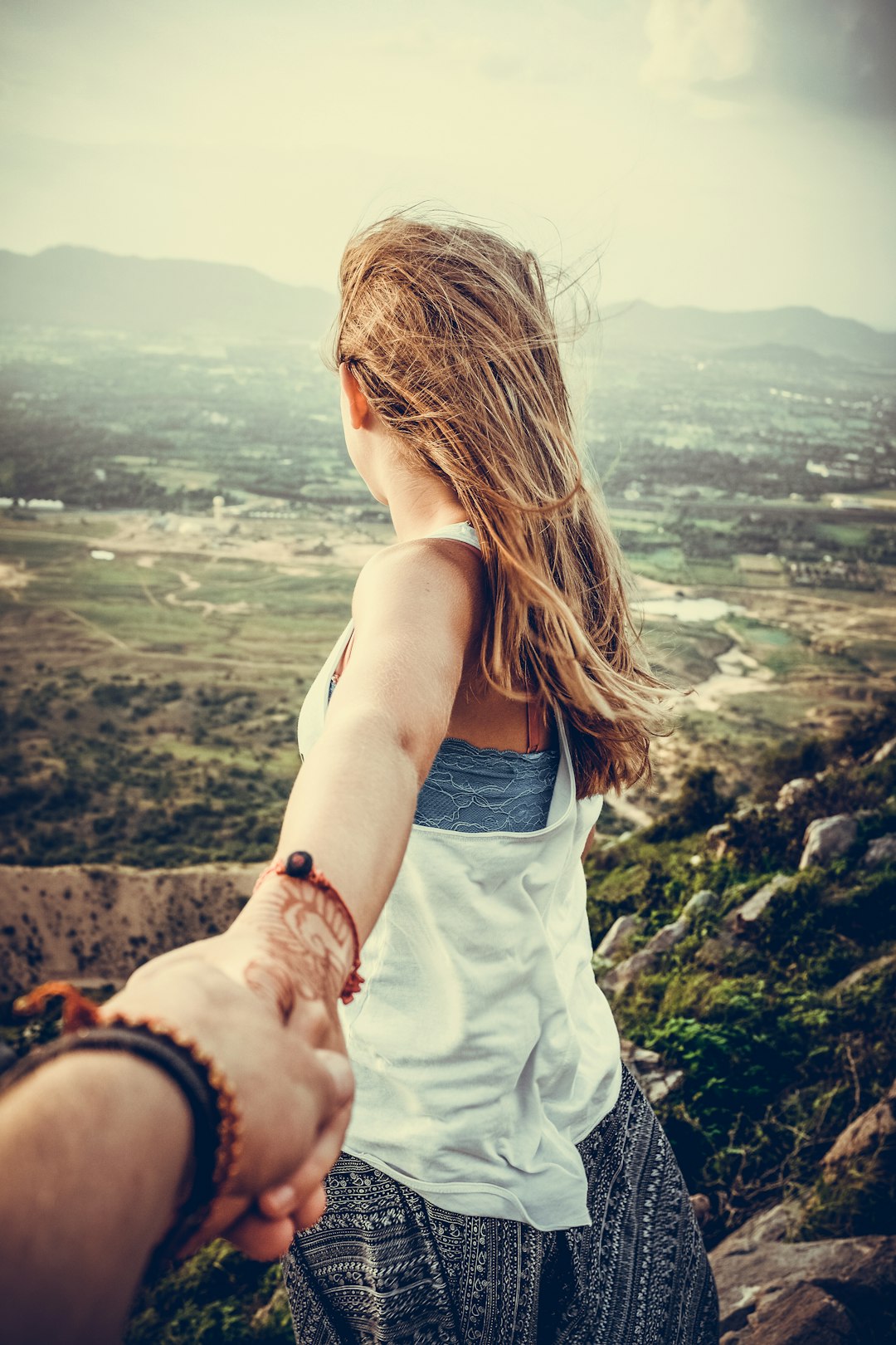person-holding-woman-wearing-white-tank-top-standing-beside-big-rocks-near-mountain-during-daytime-lcbhdzh4imq