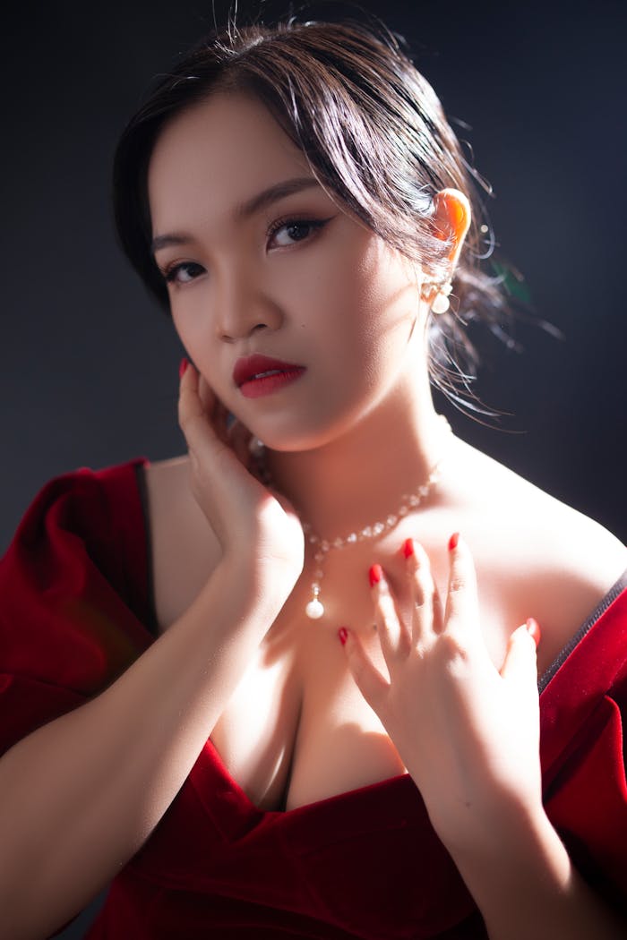 A portrait of an elegant woman in a red dress with pearls, showcasing glamour and sophistication.